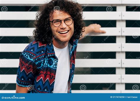 A Positive Young Man With Curly Hair Smiling Looking To The Camera