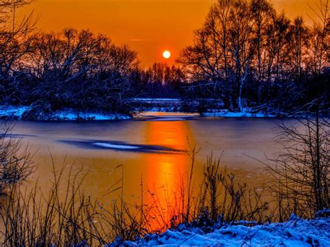 Sunset In Winter Snow River Coast Two Sun Orange Sky Reflection In