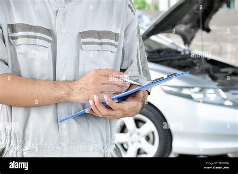 A Mechanic Holding Clipboard In Front Of Car Engine Car Checking
