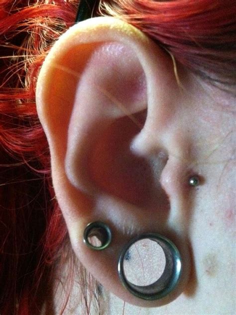 A Woman With Red Hair And Piercings On Her Ear
