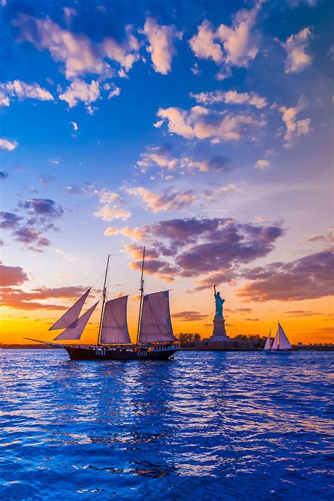 Sailing Ship In New York Harbor At Sunset Passes In Front Of The Statue