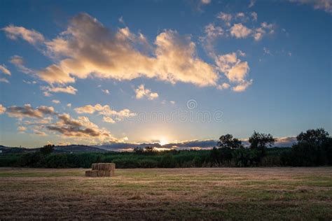 Hay On A Field During A Sunset With Clouds And The Sun Stock Image