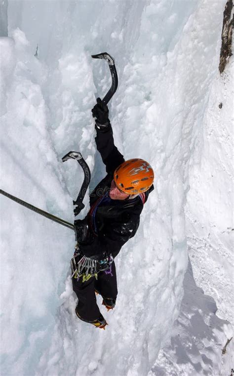 Male Ice Climber On A Steep Frozen Waterfall On A Beautiful Winter Day
