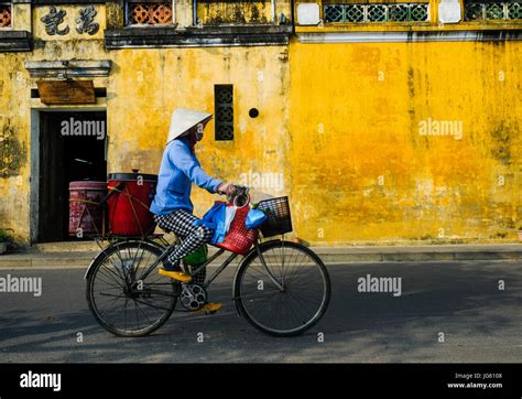 A Vietnamese Woman Rides A Bike In A Street In Hoi An Vietnam Stock