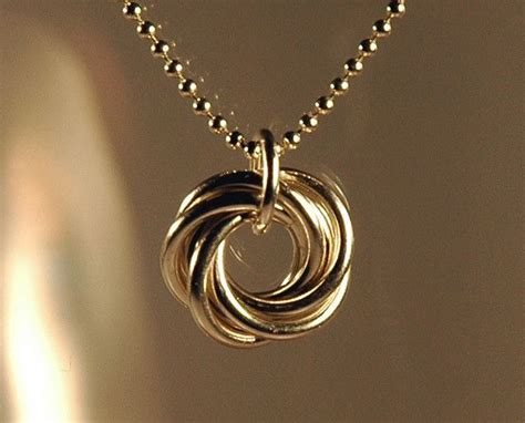 A Close Up Of A Necklace With Two Rings Hanging From Its Center On A