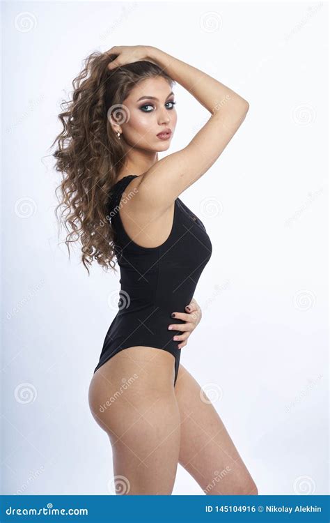 menina bonita no roupa de banho que levanta contra o fundo branco cinzento foto de stock