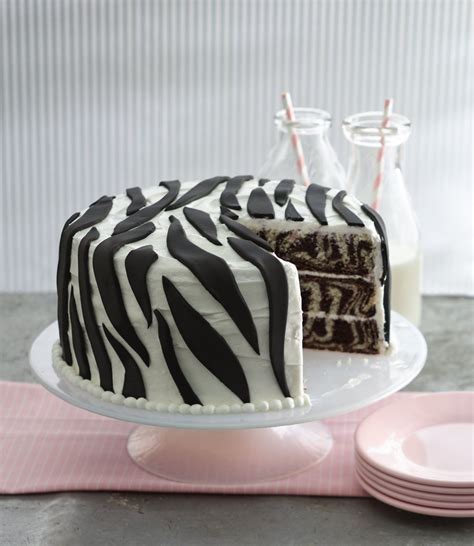 A Zebra Print Cake Sitting On Top Of A Table Next To Plates And Milk
