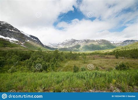 Mountains Covered By Snow Blue Sky With Clouds Green Meadow Stock