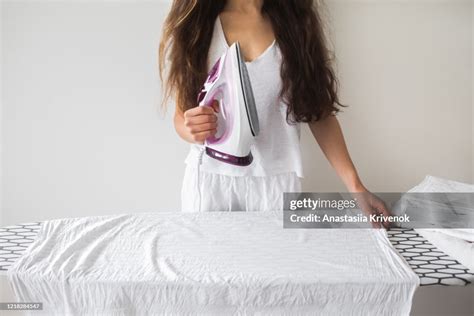Female Hand Ironing White Clothes With Pink Iron On Pressboard On White