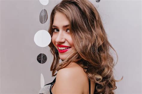 close up portrait of carefree curly girl with red lipstick looking over shoulder sensual white