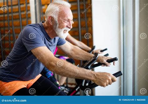 Happy Fit Mature Woman And Man Cycling On Exercise Bikes To Stay Healthy Stock Image Image Of