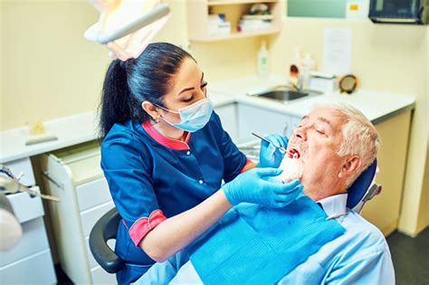 Gambar Dokter Gigi Menggunakan Cermin Bersudut Saat Memeriksa Gigi