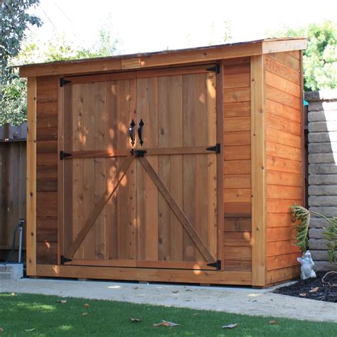 A Large Wooden Shed With A Sliding Door On The Side And Green Grass In