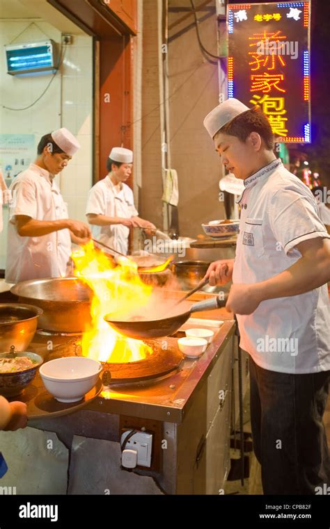 chinese chefs cooking over a traditional gas burning stove and wok at a restaurant in moslem