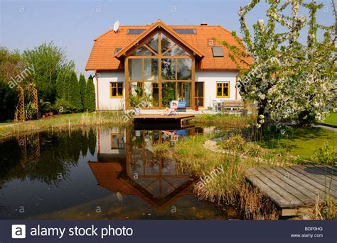 Garden Pond In Front Of A House With Conservatory And