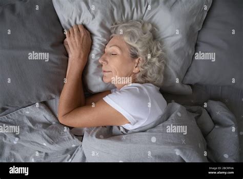 Happy Mature Woman Sleeping On Soft Pillow Under Blanket Stock Photo