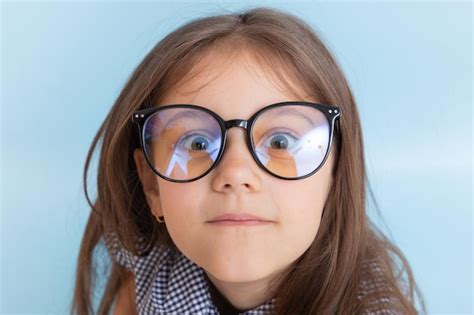 premium photo portrait of a 7 year old girl with long hair in glasses with bulging eyes looks