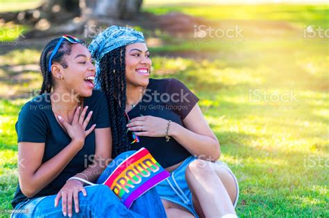 African American Young Lesbians Embracing Sitting On The Grass In A