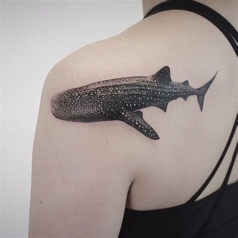 A Woman With A Tattoo On Her Shoulder Has A Shark Design On Its Back