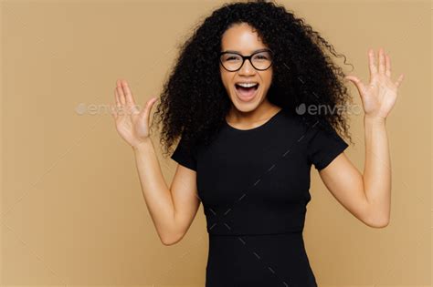 Pleased Overjoyed Woman Dances And Moves Positively Raises Palms Exclaims With Happiness Stock