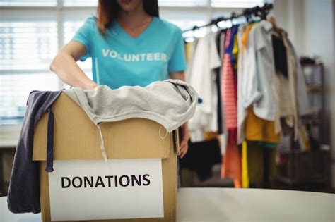 Ropa Femenina Que Sostiene Voluntarios En Caja De Donación Foto Gratis