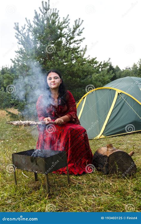 A Young Gypsy Woman Grills Meat On The Grill Near The Tent In The Smoke