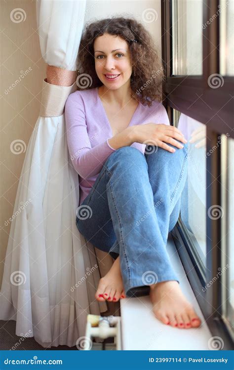 Le Femme Aux Pieds Nus S Assied Sur Le Windowsill Et Regarde Photo