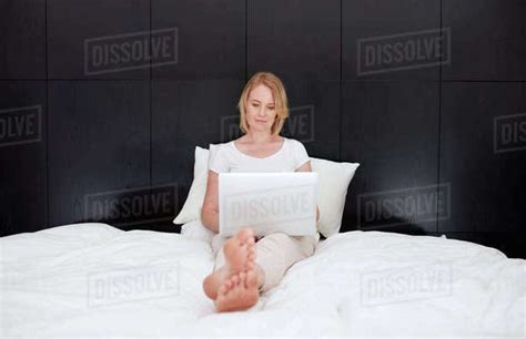 Portrait Of A Woman Sitting On Bed And Working On Her Laptop Caucasian Woman Relaxing In