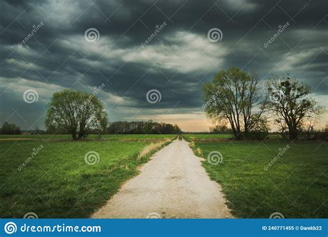 The Road Through Meadows With Trees And Dark Clouds Stock Image Image