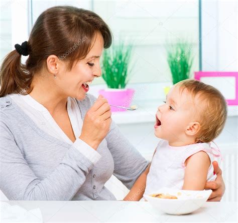 Mother Feeding Her Baby Girl With A Spoon — Stock Photo © Subbotina