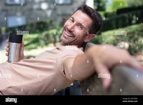Man Relaxing On Park Bench With Coffee Thermos Stock Photo Alamy