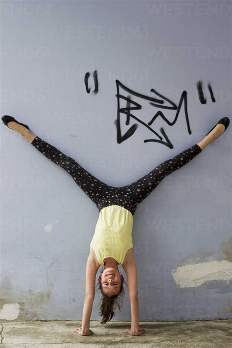 Teenage Girl Doing Handstand Against Wall Stock Photo