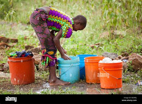 African Girl Washing Laundry By Hand In Brightly Coloured Buckets