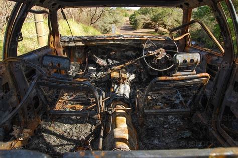Image Of A Burnt Out Car On A Country Road Near A Creek Austockphoto