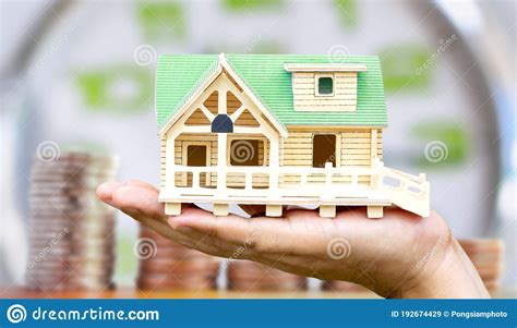 Man Holding House Model In His Hand With Coin And Clock Background The