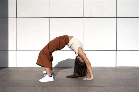 Young Woman Bending Over Backwards Against Wall During Sunny Day Stock