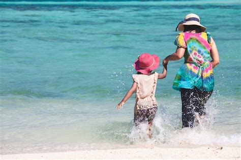 Niña Asiática De La Madre Y Del Niño Que Se Sienta En La Playa Foto