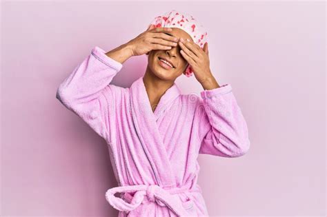 Hispanic Man Wearing Make Up Wearing Shower Towel Cap And Bathrobe Covering Eyes With Hands