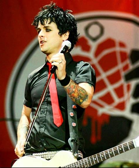 A Man In Black Shirt And Red Tie Holding A Microphone While Standing