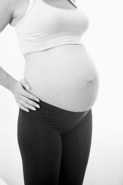 foto em preto e branco de uma mulher grávida em roupas esportivas mostrando uma grande barriga