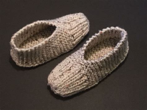 A Pair Of Knitted Slippers Sitting On Top Of A Table