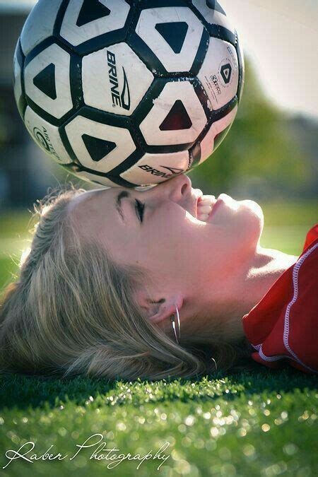 a woman laying on the ground with a soccer ball on her head in front of her face