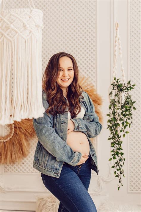 A Attractive Pregnant Woman In A Denim Jacket With A Naked Tummy Stock