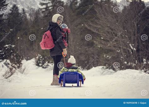 Mother Pulling Her Child Through Winter Snow On A Sledge Stock Photo