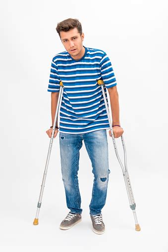Disabled Young Man Trying To Walk With Crutches Over White Background