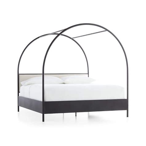 A Bed With An Arched Metal Frame And White Sheets