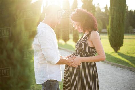 Man Touching Belly Of Pregnant Wife In Park Stock Photo Dissolve