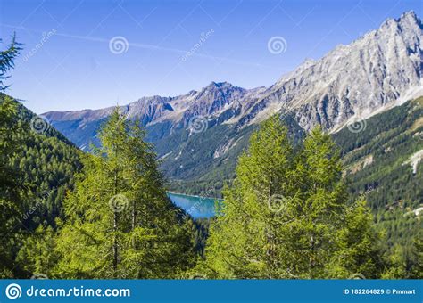 Bright Blue Mountain Lake Under Blue Sky With Woods Stones And Snow