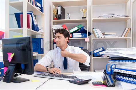 Businessman Working In The Office With Piles Of Books And Papers