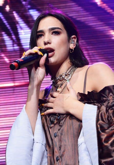 A Woman Holding A Microphone In Her Right Hand And Wearing An Outfit